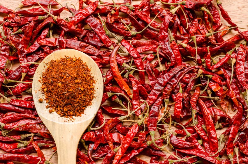 Dried red chillies with wooden spoon of crushed chilli flakes